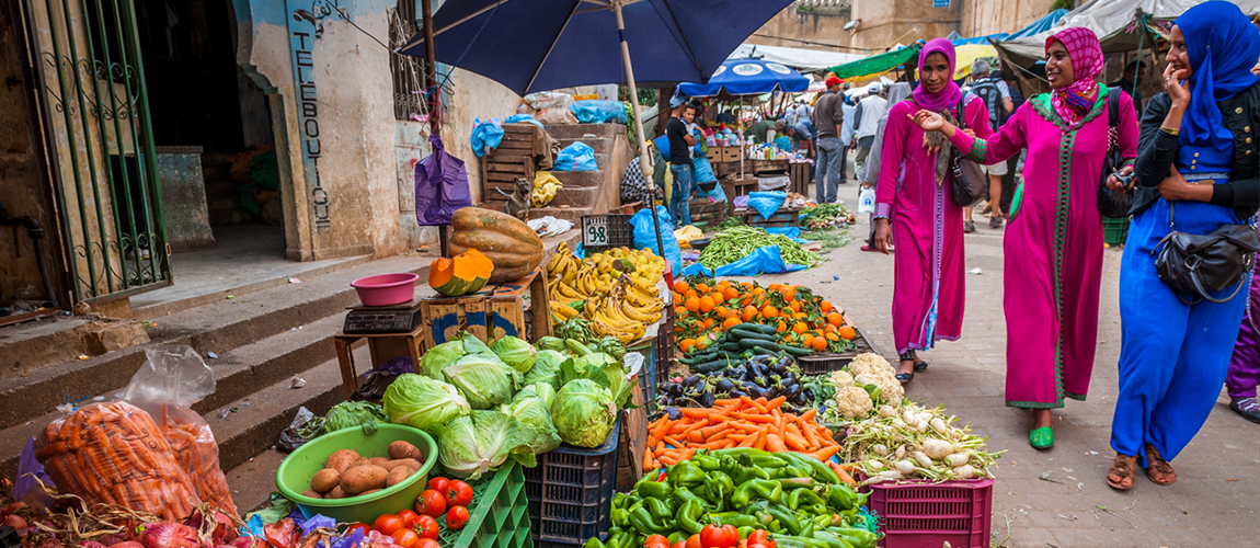 Women walking along the open market with a wide choice of fresh fruit and vegetables